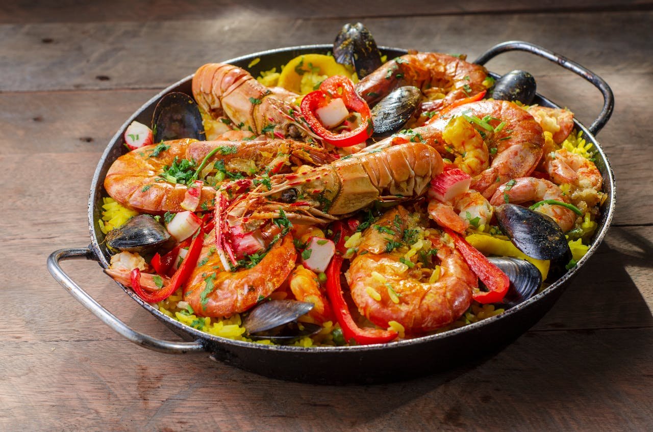 Vibrant seafood paella with prawns, mussels, and vegetables in an outdoor rustic setting.