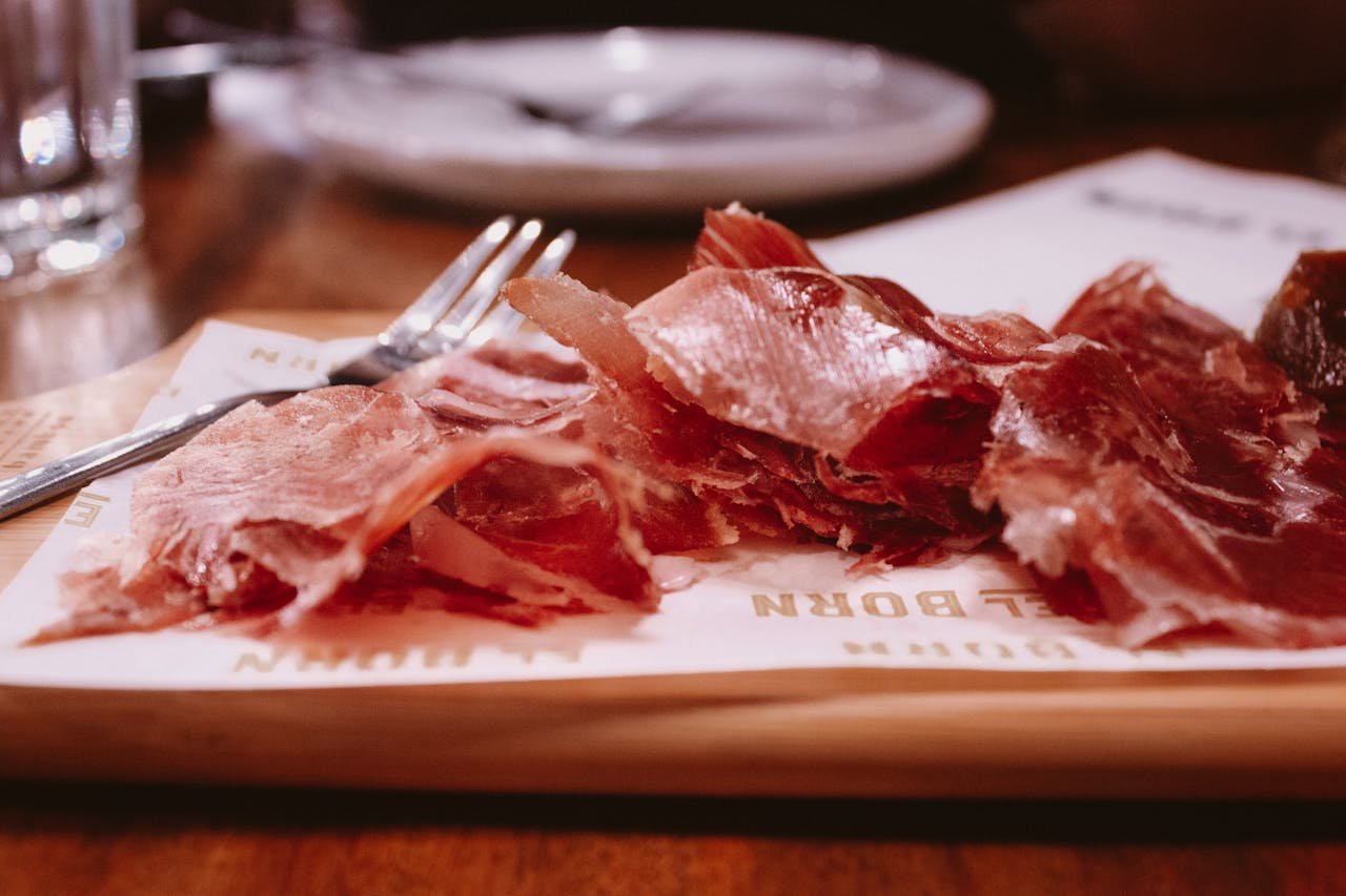 Delicious thinly sliced cured meat on a wooden tray, ready to savor.